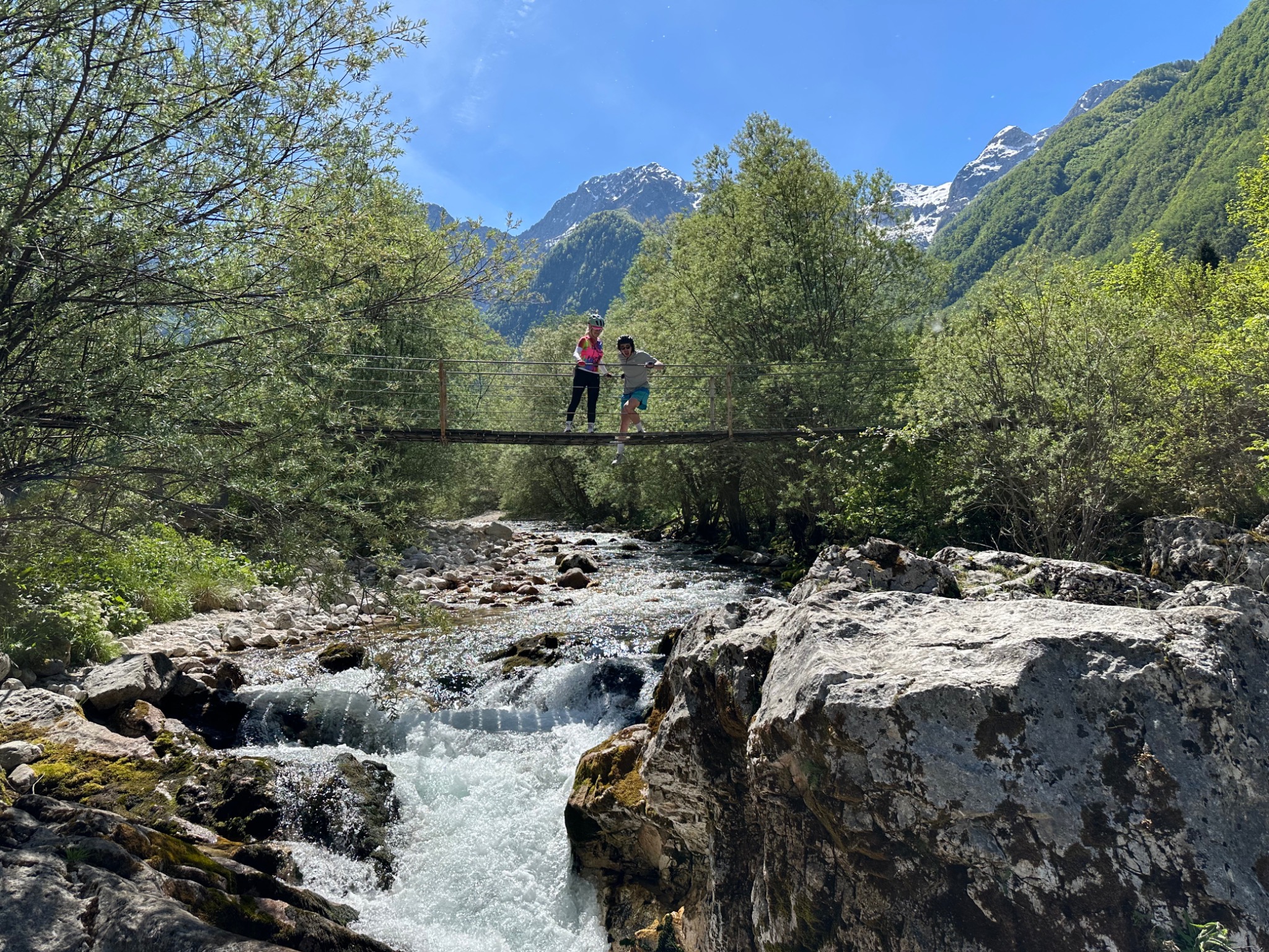 Travellers crossing a suspension bridge above an alpine stream in Slovenia